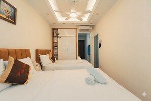 Habitación de hotel con cama, ventilador de techo, una puerta y aire acondicionado de pared.