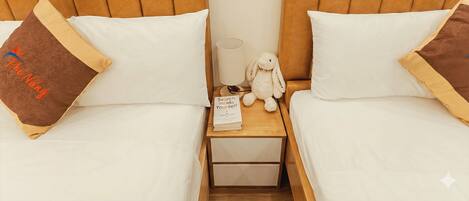 A double bed with a wooden headboard, a small bedside table with a lamp, a stuffed toy, and a book titled "Search Inside Yourself".