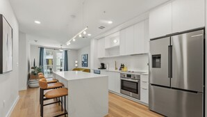 Une cuisine moderne dotée d’un îlot central, d’appareils électroménagers en acier inoxydable et d’un revêtement de sol en bois.