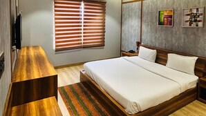 A modern bedroom with a wooden bed, a desk, and a ceiling fan. - The Nature Resort (Rishikesh)