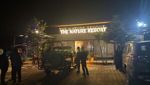 The entrance to The Nature Resort with a paved driveway, a jeep, and a van parked in front. - The Nature Resort (Rishikesh)
