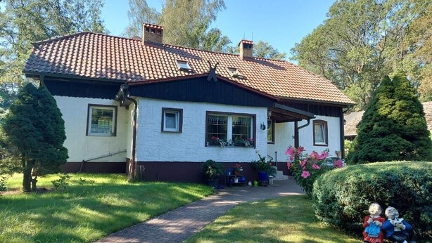 Ein zweistöckiges Haus mit Ziegeldach, einer Veranda und einem Weg zum Eingang.