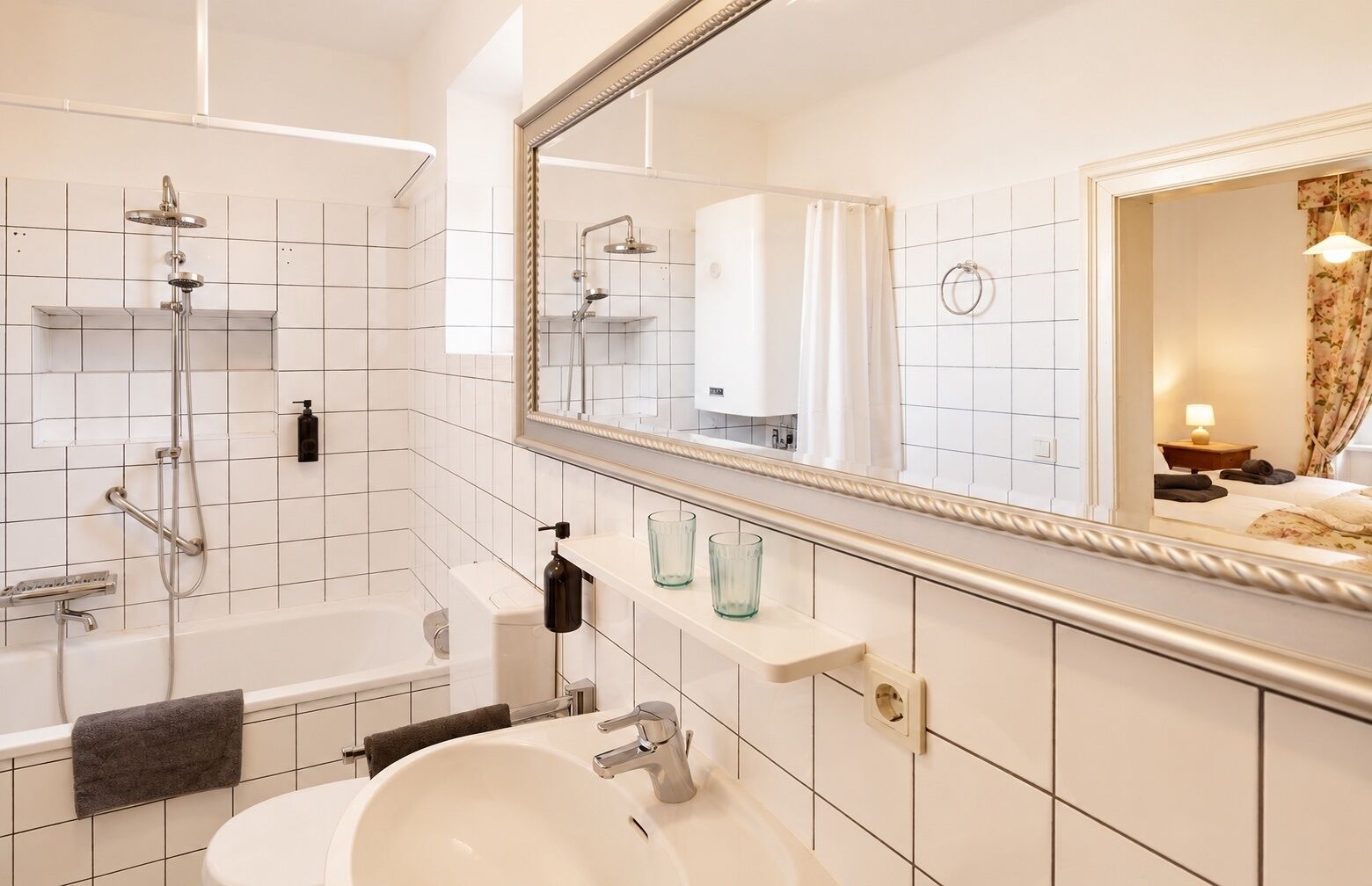 A modern bathroom with a bathtub, shower, and sink, a mirror, and a towel rack.