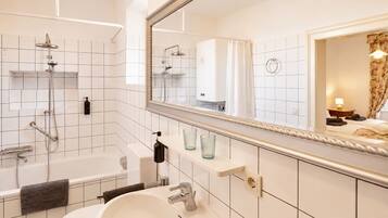A modern bathroom with a bathtub, shower, and sink, a mirror, and a towel rack.