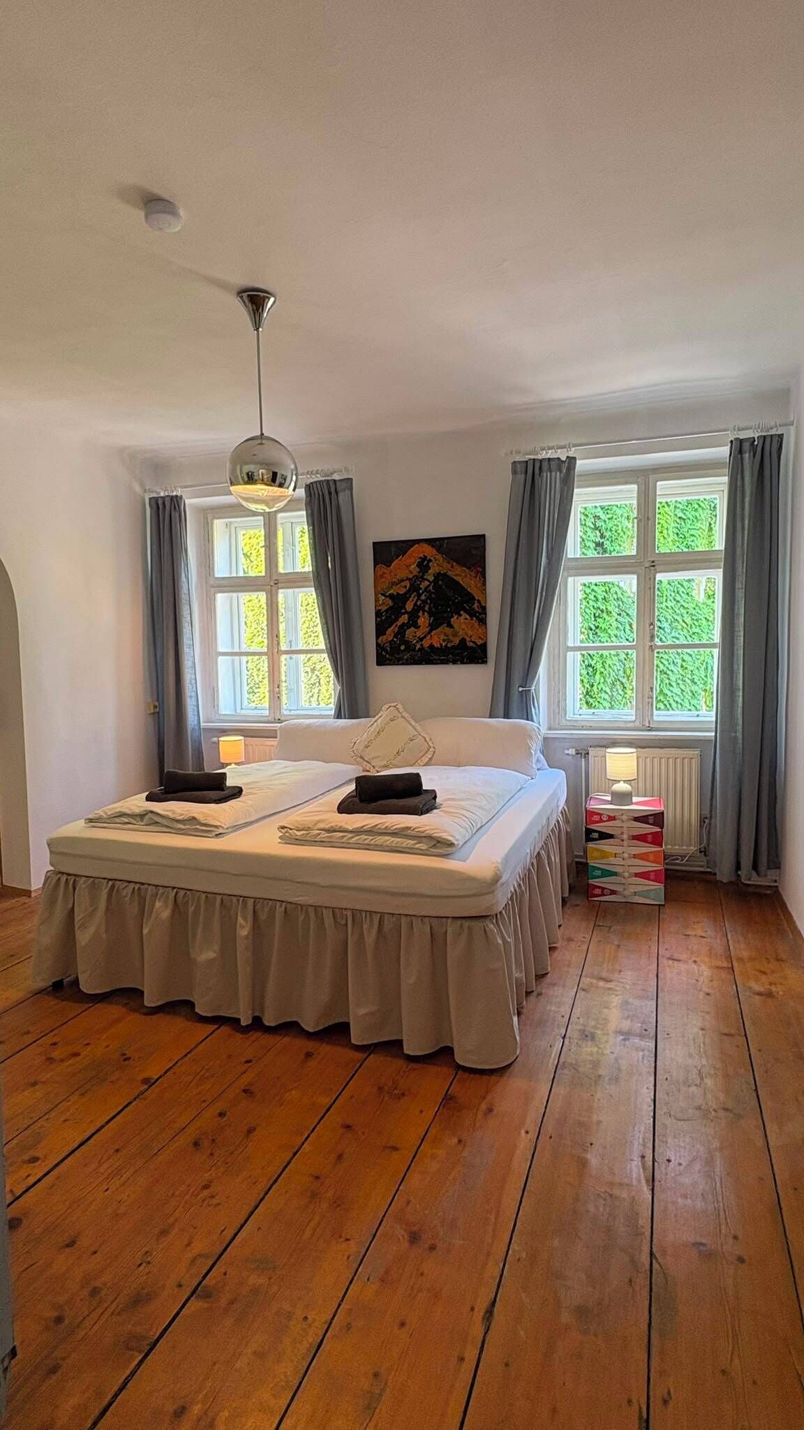 Et soveværelse med en stor seng, en loftlampe, en radiator og et vindue med gardiner.