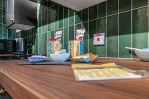 Een aanrecht met een magnetron, een koffiezetapparaat en een zak koffiecups.