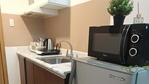 A compact kitchen with a refrigerator, microwave, and sink. - Cozy Condo Near US Embassy in Manila (Manila)