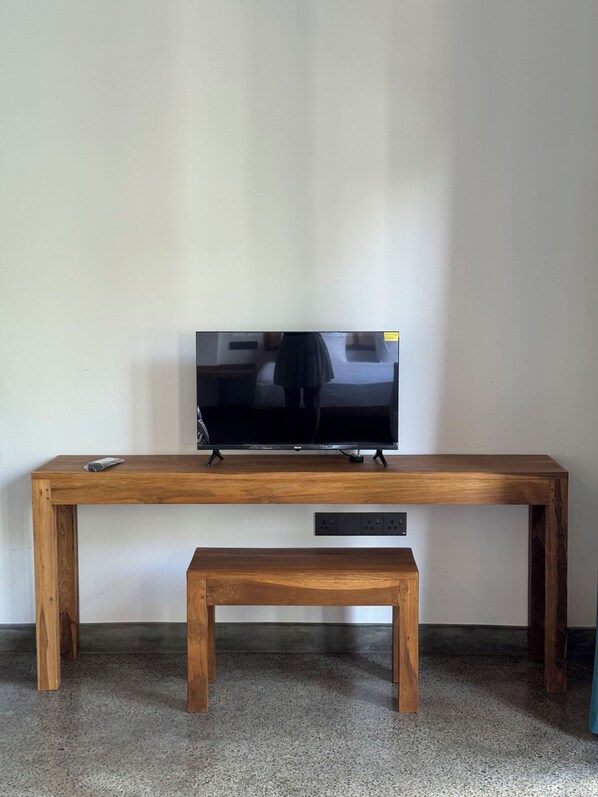 A wooden TV stand with a flat-screen TV on top and a bench below. - Cielo Hiriketiya (Dikwella)