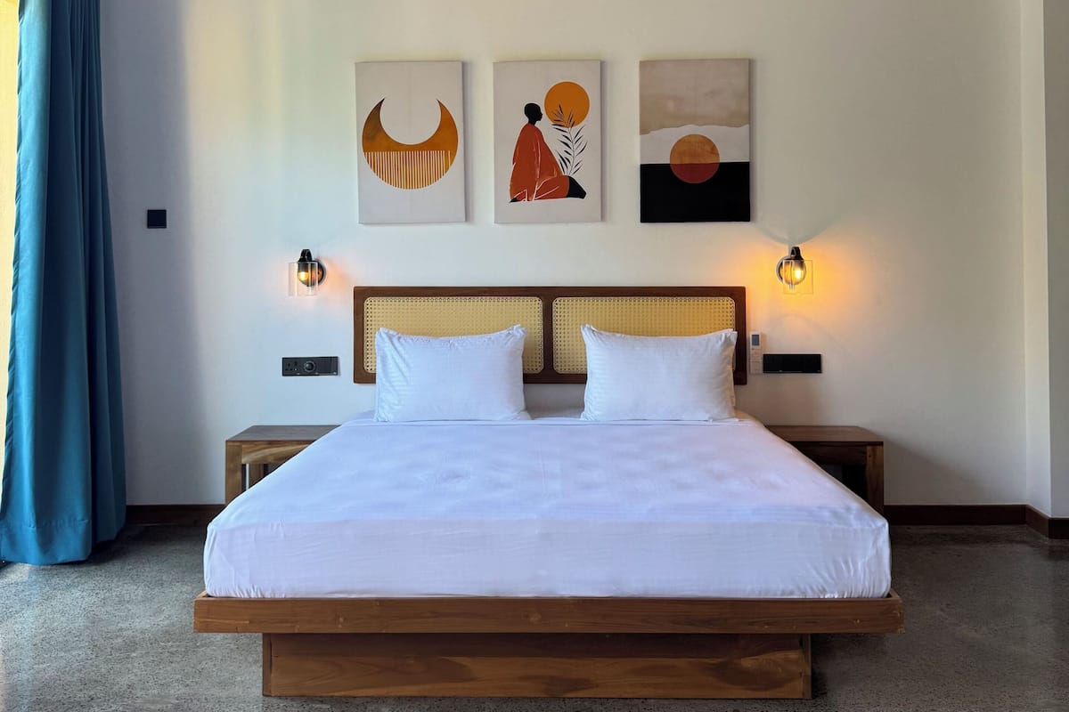 A modern hotel room with a large bed, two bedside tables, and a ceiling fan.
