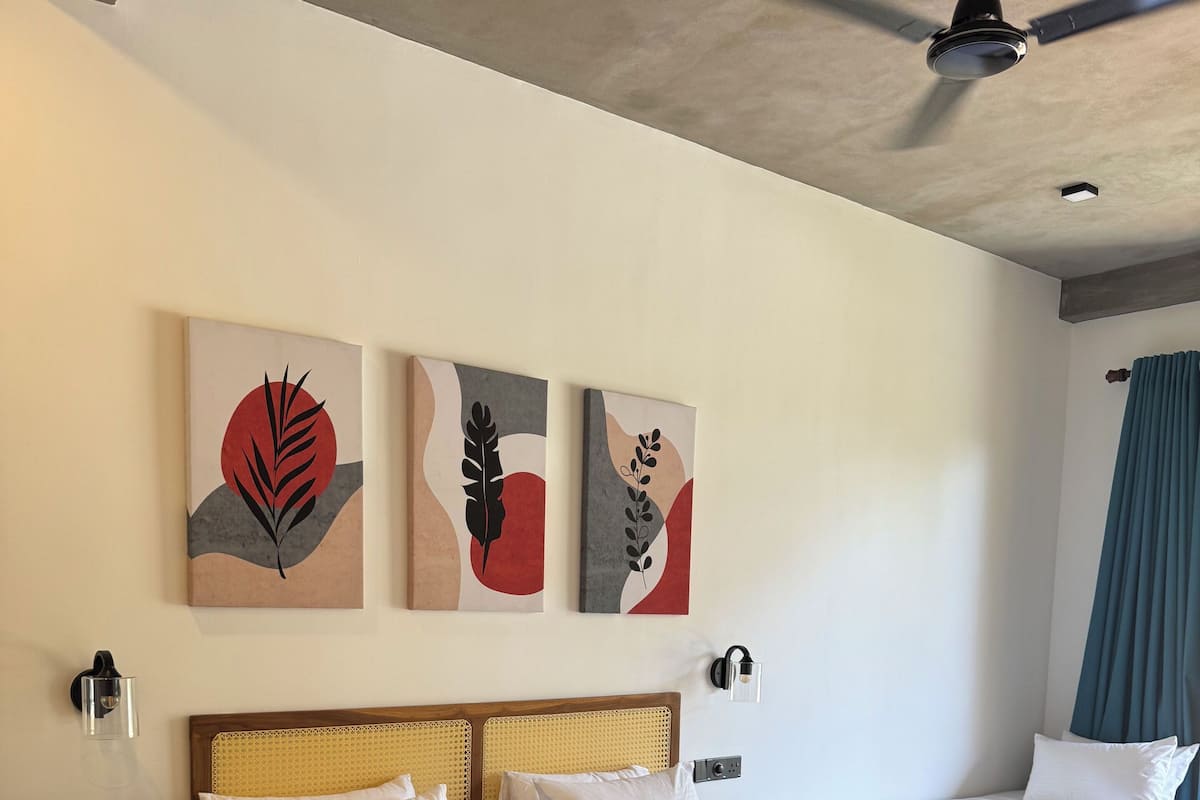 A hotel room with a large bed, a smaller bed, a ceiling fan, and artwork on the wall.