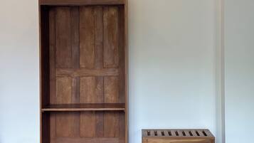 A wooden cabinet with multiple shelves and a matching bench against a plain wall.
