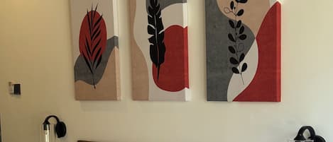 A hotel room with a large bed, two bedside tables, and three wall-mounted artworks.