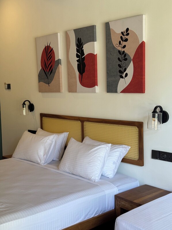 A hotel room with a large bed, two bedside tables, and three wall-mounted artworks. - Cielo Hiriketiya (Dikwella)