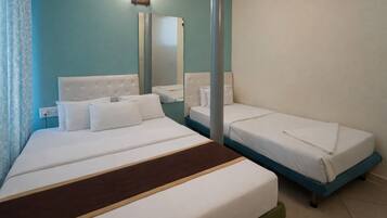 A hotel room with two beds, a mirror, a light fixture, and a window with curtains.