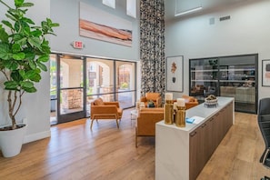 A reception area with a modern design, featuring a reception desk, seating area, and a large window providing a view of the outdoors. - ASU Area Getaway with Pool, Spa, Gym & Parking (Tempe)