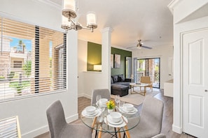 A dining area with a glass table set for four, a sofa, and a ceiling fan. - ASU Area Getaway with Pool, Spa, Gym & Parking (Tempe)