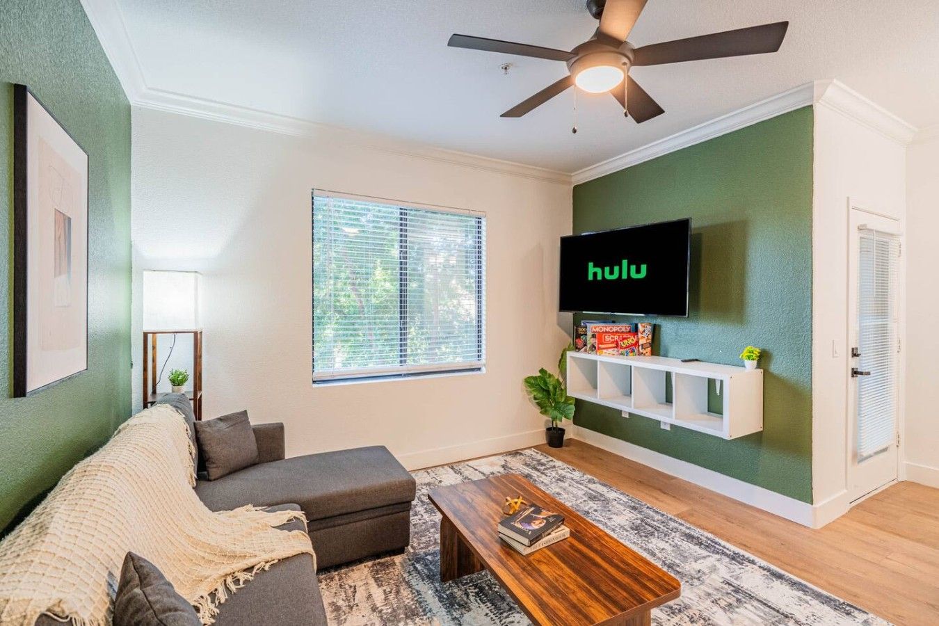 A living room with a sofa, coffee table, and a TV mounted on the wall.