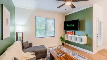 A living room with a sofa, coffee table, and a TV mounted on the wall.