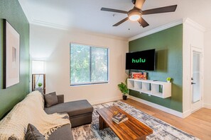A living room with a sofa, coffee table, and a TV mounted on the wall. - Near Diablo Stadium & ASU-HotTub,Pool,Gym,Parking (Tempe)