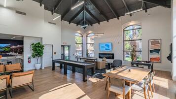 A spacious indoor area with a high ceiling, a fireplace, a television, and a pool table.