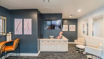 A modern reception area with a desk, chairs, artwork, a flat-screen TV, and a sofa.