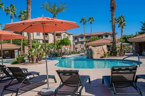 A pool area with lounge chairs and umbrellas, surrounded by palm trees and a building with a tiled roof. - Near Diablo Stadium & ASU-HotTub,Pool,Gym,Parking (Tempe)