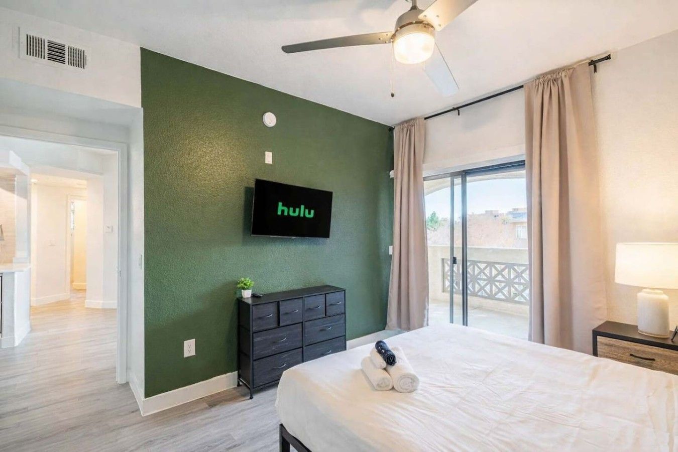 Ein Hotelzimmer mit Bett, Wandfernseher, Deckenventilator und Blick ins Freie.