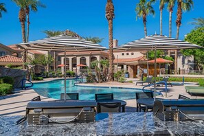 Zona de piscina amb gandules, ombrel·les i una piscina blava i cristal·lina.