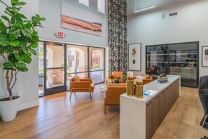 Un espace d’accueil au design moderne, comprenant un comptoir d’accueil, un coin salon et une grande fenêtre offrant une vue sur l’extérieur.