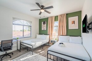 A hotel room with two beds, a desk, a chair, a ceiling fan, and a window with blinds. - 2BR-2BA Near ASU & Arizona Mills | Pool & W/D (Tempe)