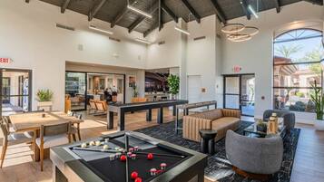 A spacious lobby with a pool table, seating area, and a view of the outdoor patio.