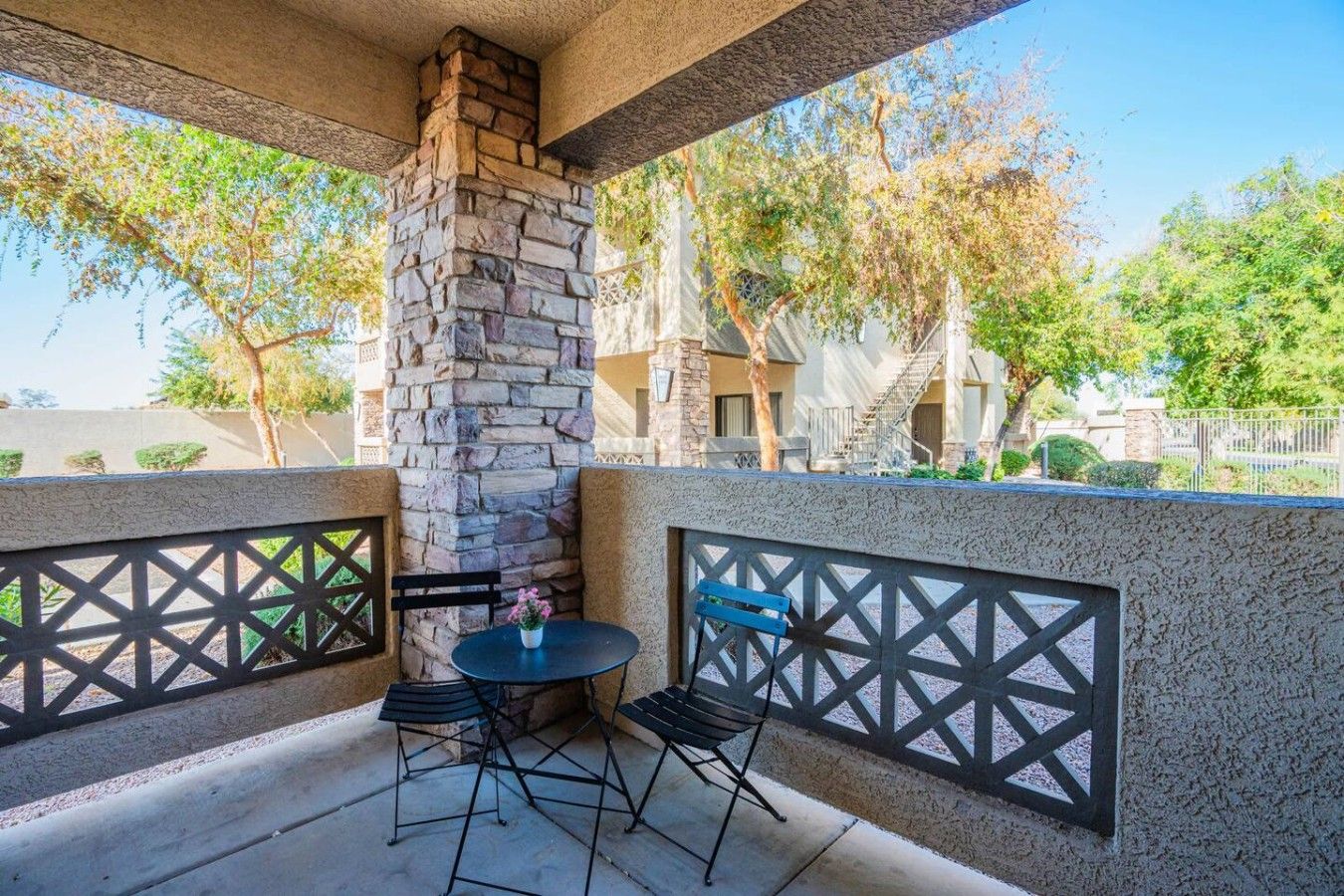 A patio area with a stone fireplace, two tables, and chairs.