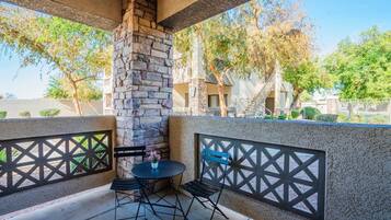A patio area with a stone fireplace, two tables, and chairs.