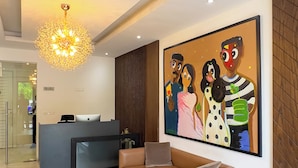 A modern reception area with a desk, a sofa, and a large abstract painting. - Cozy studio apt in Accra - Ghana with AC and gym access (Accra)