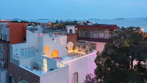 Une terrasse sur le toit offrant une vue sur la mer, avec un espace repas et un petit jardin.