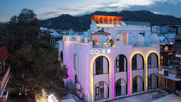 Un bâtiment moderne doté de fenêtres en arc de cercle et d’une terrasse sur le toit.