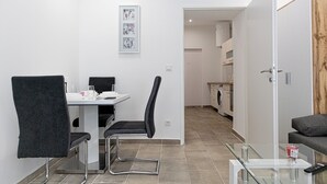 A modern, well-lit room with a dining table, chairs, a glass coffee table, a sofa, and a wooden accent wall. - Central Vienna Elegant 1BR Apartment (Vienna)