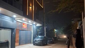 Un immeuble dont le rez-de-chaussée abrite un commerce fermé et devant lequel est garée une voiture.