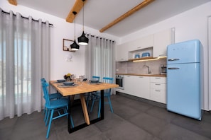 Une cuisine moderne avec un réfrigérateur bleu, des armoires blanches et une table à manger en bois, assortie de chaises bleues.