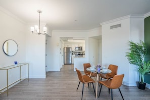 Une cuisine moderne équipée d’appareils électroménagers en acier inoxydable, un coin repas avec une table ronde et des chaises, et un couloir menant à l’espace de vie.