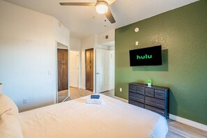 A hotel room with a bed, a TV mounted on the wall, a dresser, and a ceiling fan. - Close ASU&Diablo Stadium - GymHotTubParkingPool (Tempe)