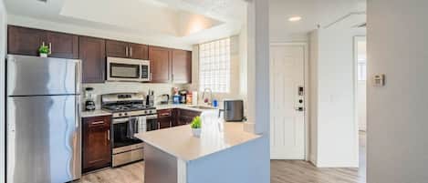 A modern kitchen with stainless steel appliances, dark wood cabinets, and a central island.