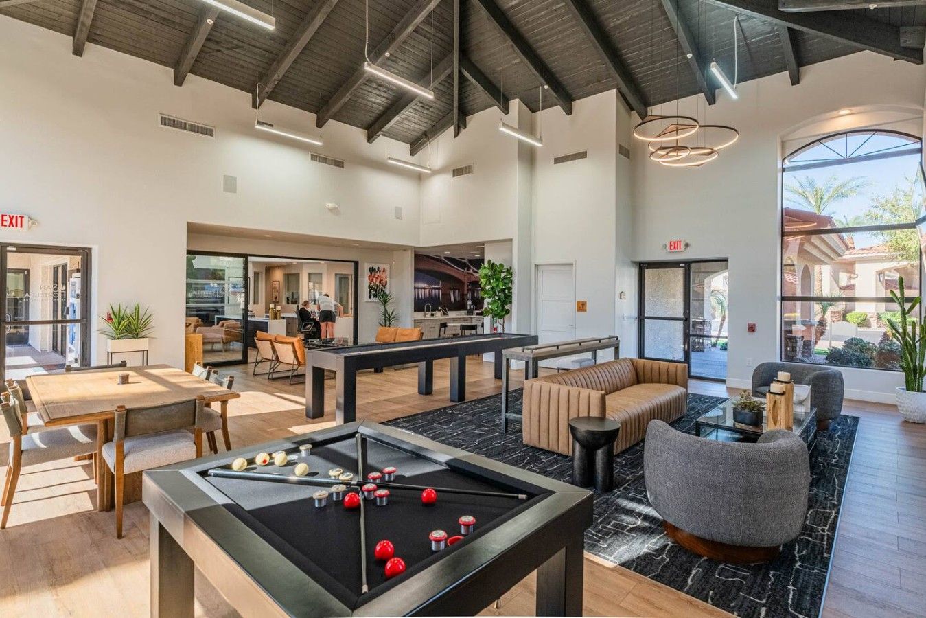 A spacious lobby with a pool table, seating area, and a view of the outdoor patio.