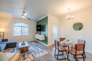 A modern living room with a flat-screen TV, a ceiling fan, and a dining area with a table and chairs. - Close ASU&Diablo Stadium - GymHotTubParkingPool (Tempe)