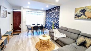 Una sala de estar moderna con un sofá gris, una mesa de centro redonda y un comedor con mesa y sillas.