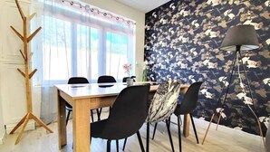 Un comedor con una mesa y sillas de madera, un perchero y un zócalo estampado.