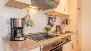 Una cocina con electrodomésticos de acero inoxidable, encimera de granito y un colgador para utensilios.