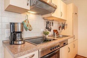 Eine Küche mit Edelstahlgeräten, einer Granit Arbeitsplatte und einem hängenden Küchenutensilienhalter.