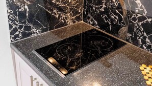 Una cucina con piano di lavoro in marmo nero, cappa aspirante in acciaio inossidabile e piano cottura a gas integrato.