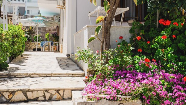 Un vialetto in pietra conduce a un edificio con il cartello degli Appartamenti Marlenis Garden.